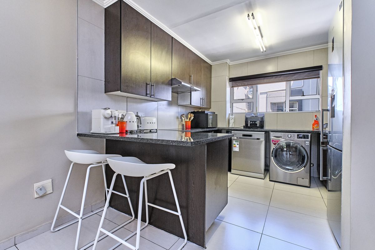 Modern kitchen featuring dark wood cabinetry, granite countertops, a breakfast bar, and integrated space for laundry and dishwasher appliances.