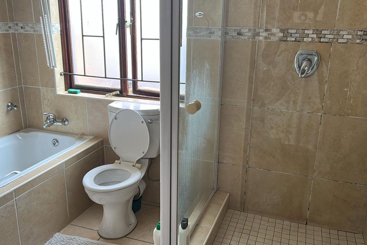A functional bathroom featuring a built-in bathtub, a separate glass-enclosed shower, and tiled walls and flooring.