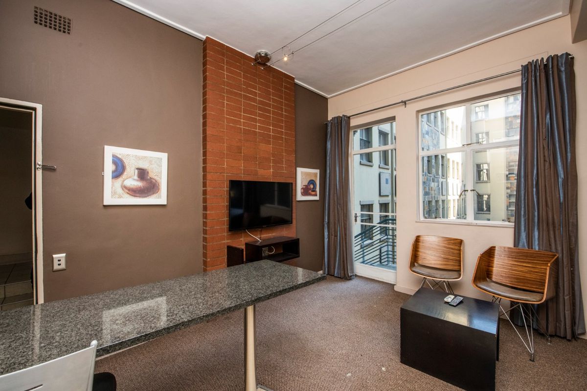Living area featuring a brick feature wall, granite-topped breakfast bar, and access to a small balcony with urban views.