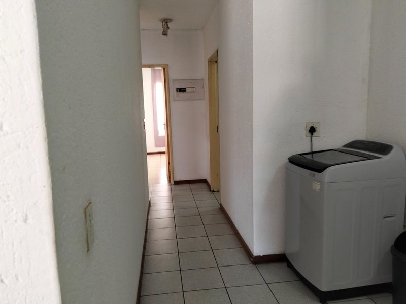 A functional hallway featuring tiled flooring and access to adjacent rooms, providing a neutral base for potential interior updates.
