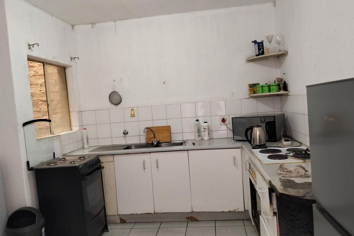 A functional kitchen featuring white cabinetry, tiled backsplash, and built-in cooking appliances, offering potential for modernization and cosmetic updates.