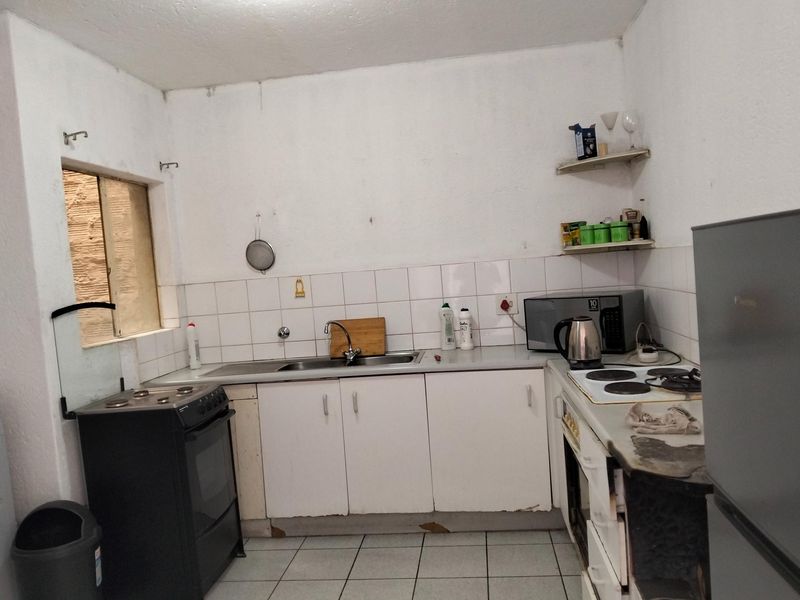 A functional kitchen featuring white cabinetry, tiled backsplash, and built-in cooking appliances, offering potential for modernization and cosmetic updates.