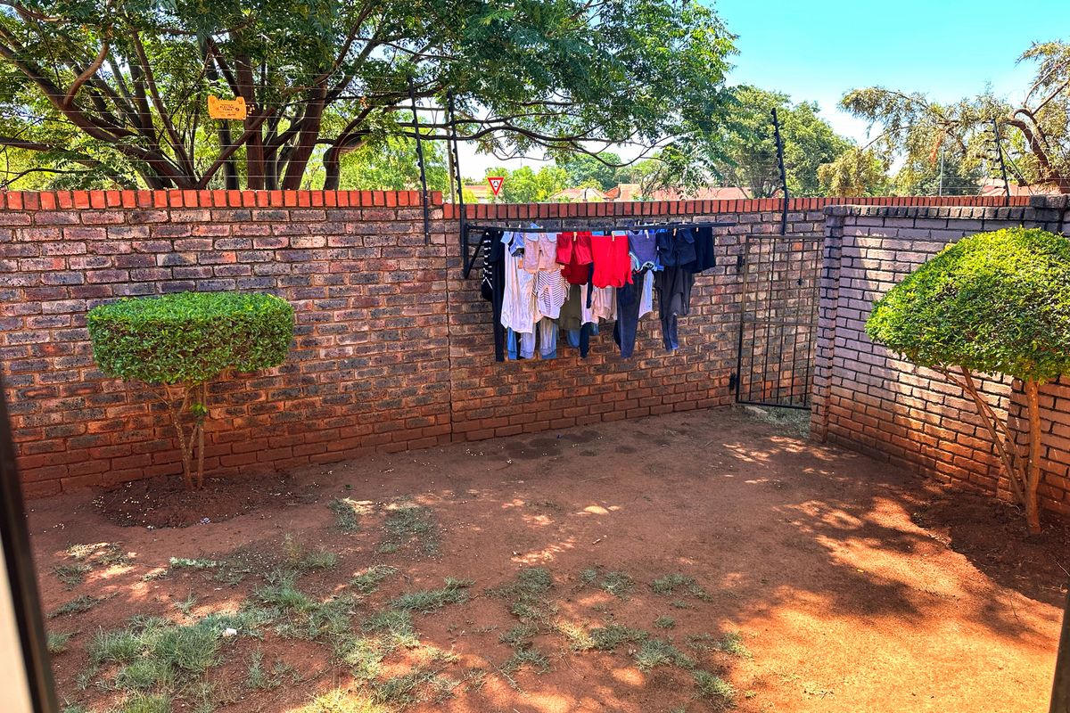 A private rear courtyard featuring a brick boundary wall, integrated electric fencing, and a metal security gate.