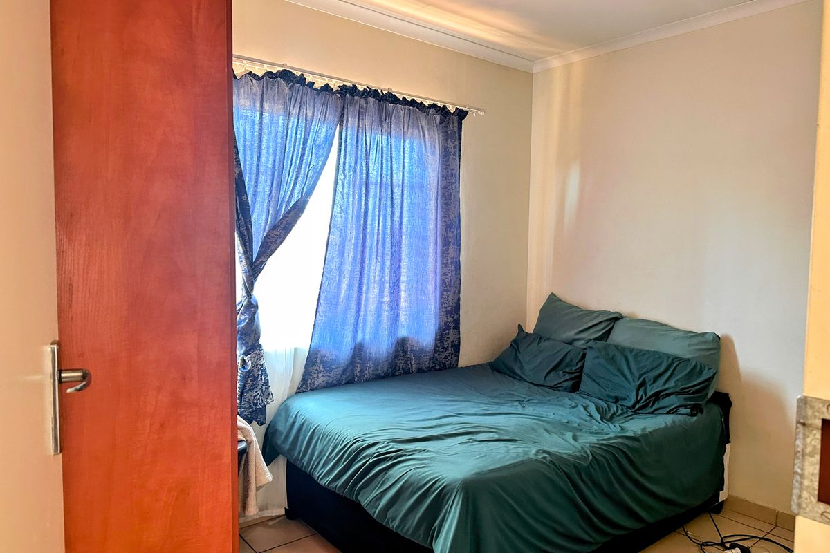 A standard bedroom featuring tiled flooring and a window with curtain fixtures.