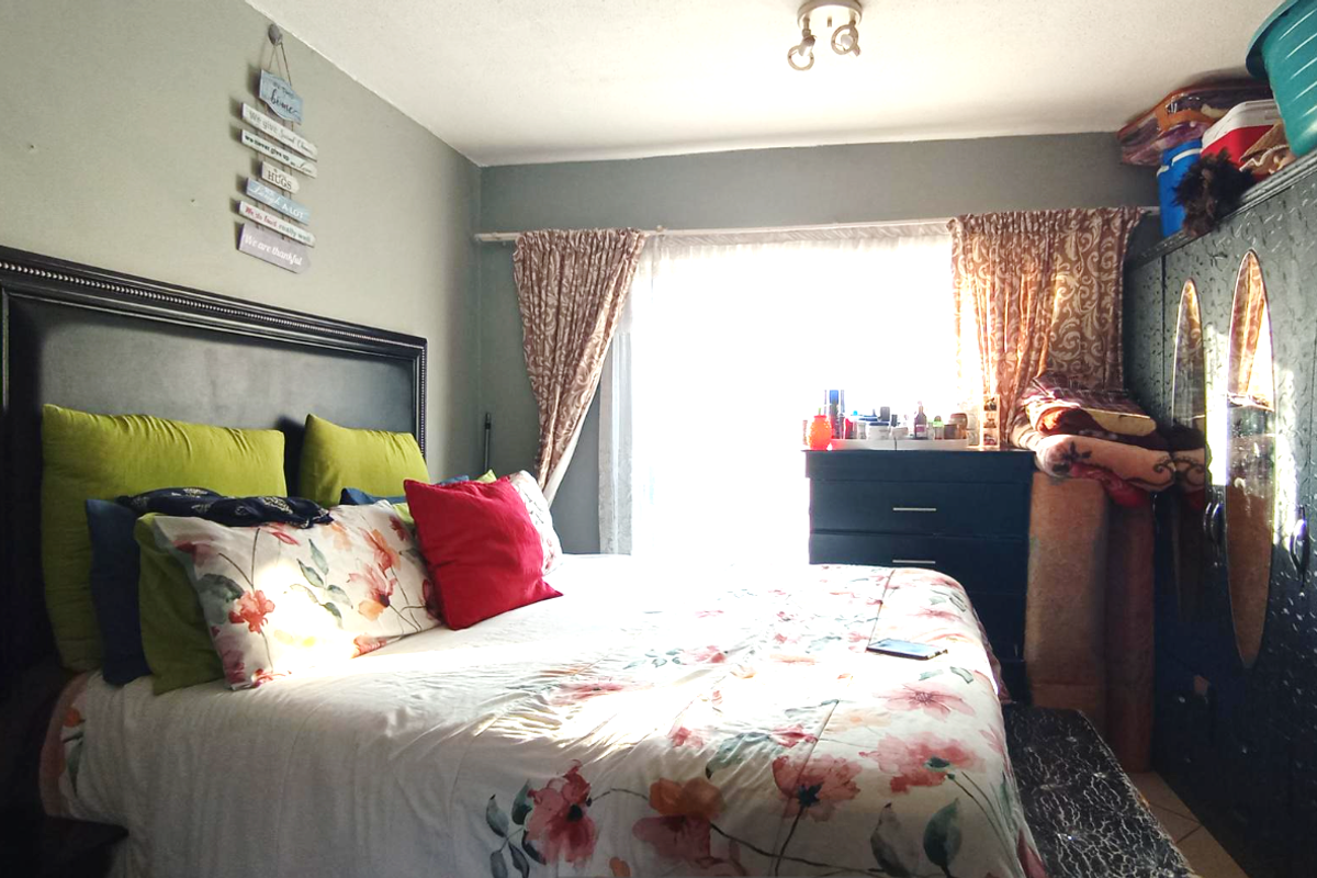 A bedroom featuring a large window with curtains, providing natural light to the space.