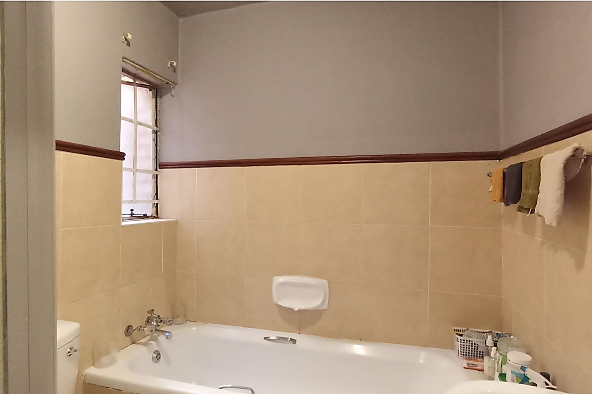 A functional bathroom featuring a built-in bathtub, wall-mounted soap dish, and tiled splashbacks with a decorative wooden dado rail.