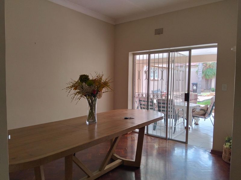 Dining area featuring polished parquet flooring and a sliding glass door with security gate leading to an outdoor patio.