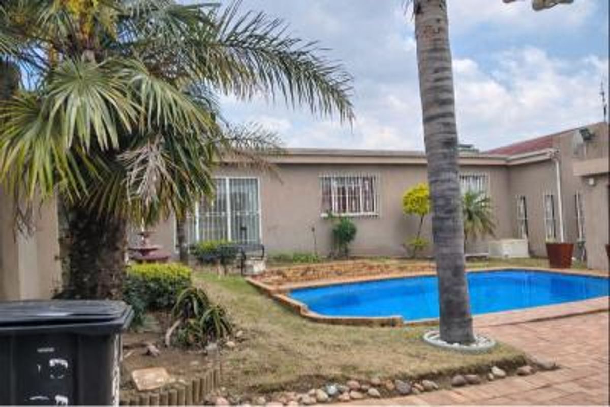 Rear exterior view featuring a swimming pool, paved patio area, and established garden with security bars on the windows.