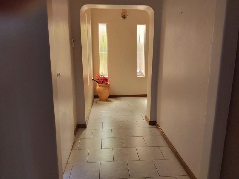 A bright, tiled hallway featuring an arched entryway and vertical windows, providing a clean and neutral transition space within the home.