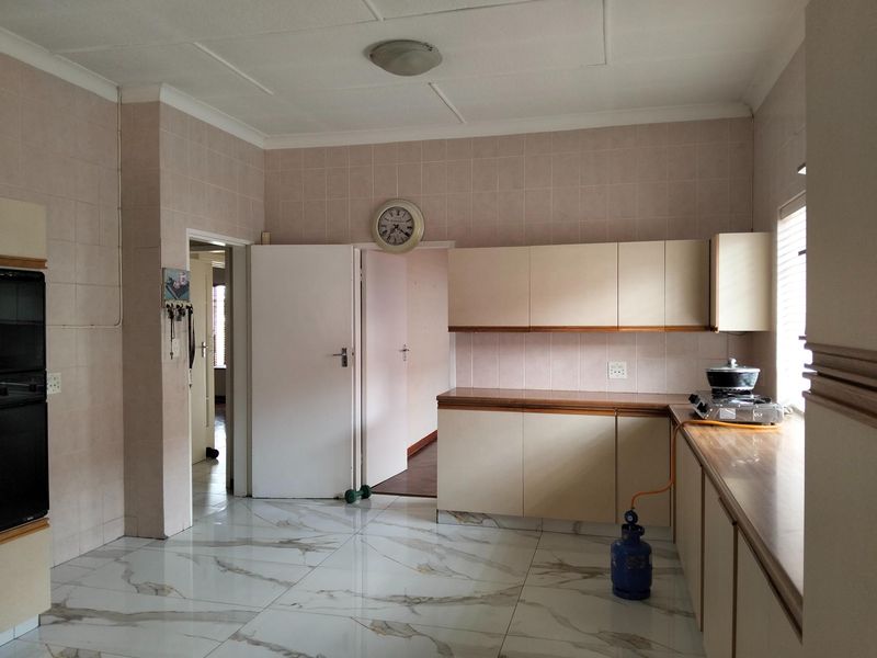 A functional kitchen featuring built-in cabinetry, tiled walls, and modern marble-look floor tiles, offering a clean and spacious layout for potential updates.