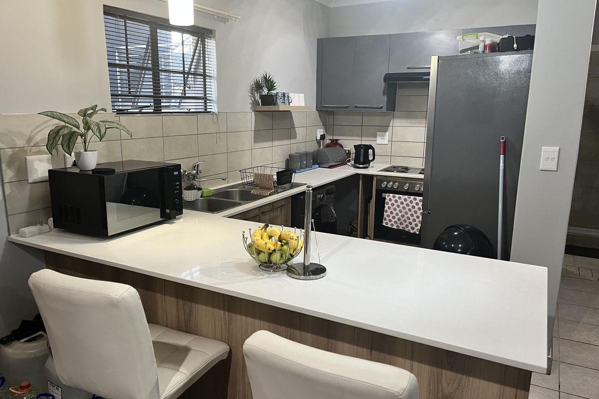 Modern kitchen featuring a breakfast bar, built-in cabinetry, tiled backsplash, and integrated oven with extractor fan.