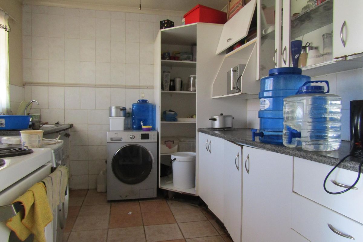 A functional kitchen featuring built-in cabinetry, tiled backsplash, and integrated laundry plumbing, offering potential for modernization and aesthetic updates.