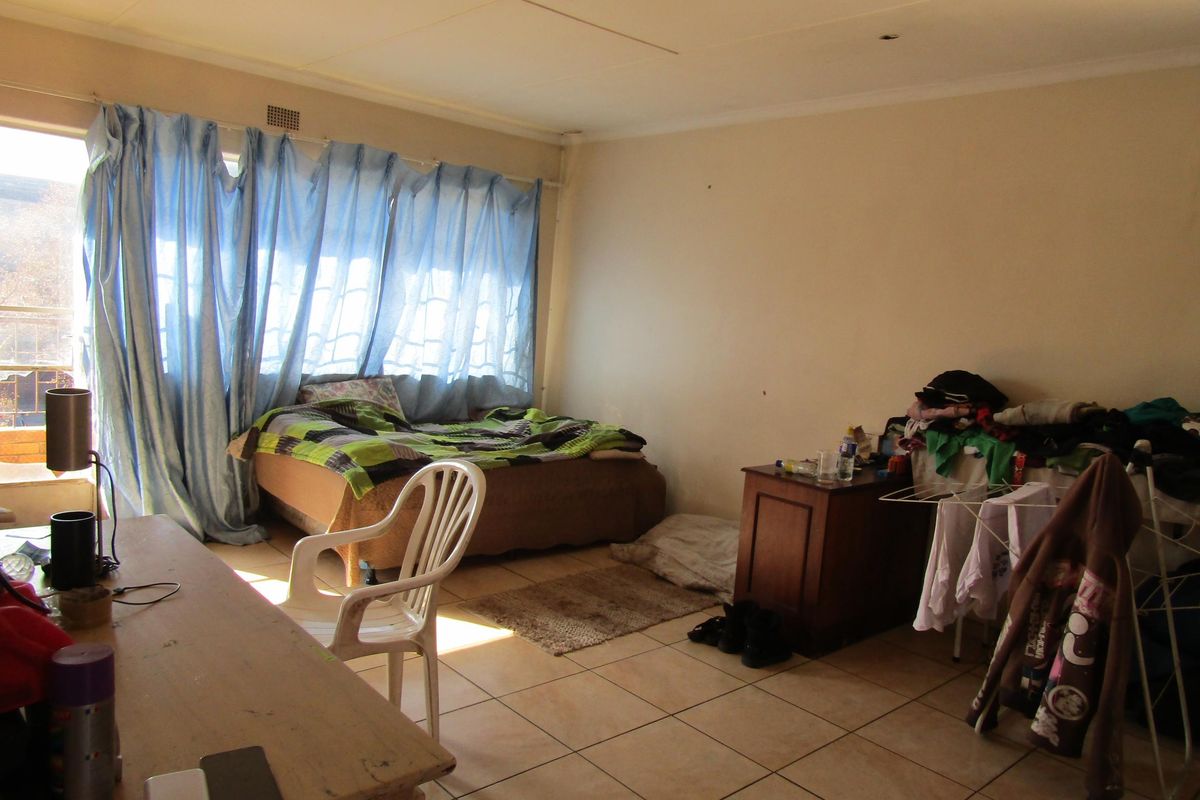 A bedroom featuring tiled flooring and access to a balcony through a sliding door, requiring cosmetic updates to improve its overall condition.