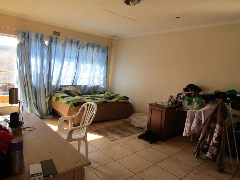A bedroom featuring tiled flooring and access to a balcony through a sliding door, requiring cosmetic updates to improve its overall condition.