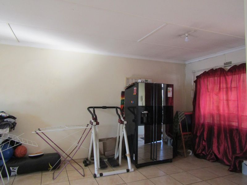 A living room area featuring neutral wall finishes and tiled flooring, providing a functional space for daily living.