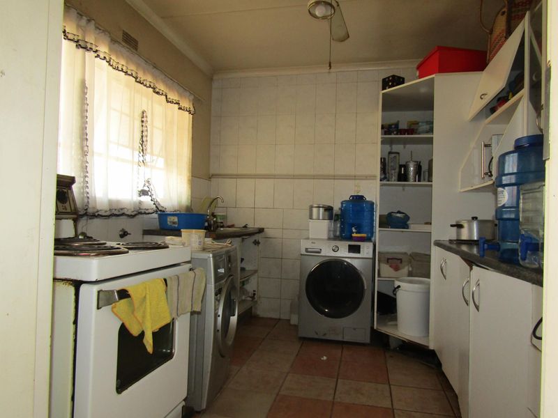 A functional kitchen featuring tiled flooring, a tiled backsplash, built-in cabinetry, and a freestanding stove, offering potential for modernization and layout optimization.