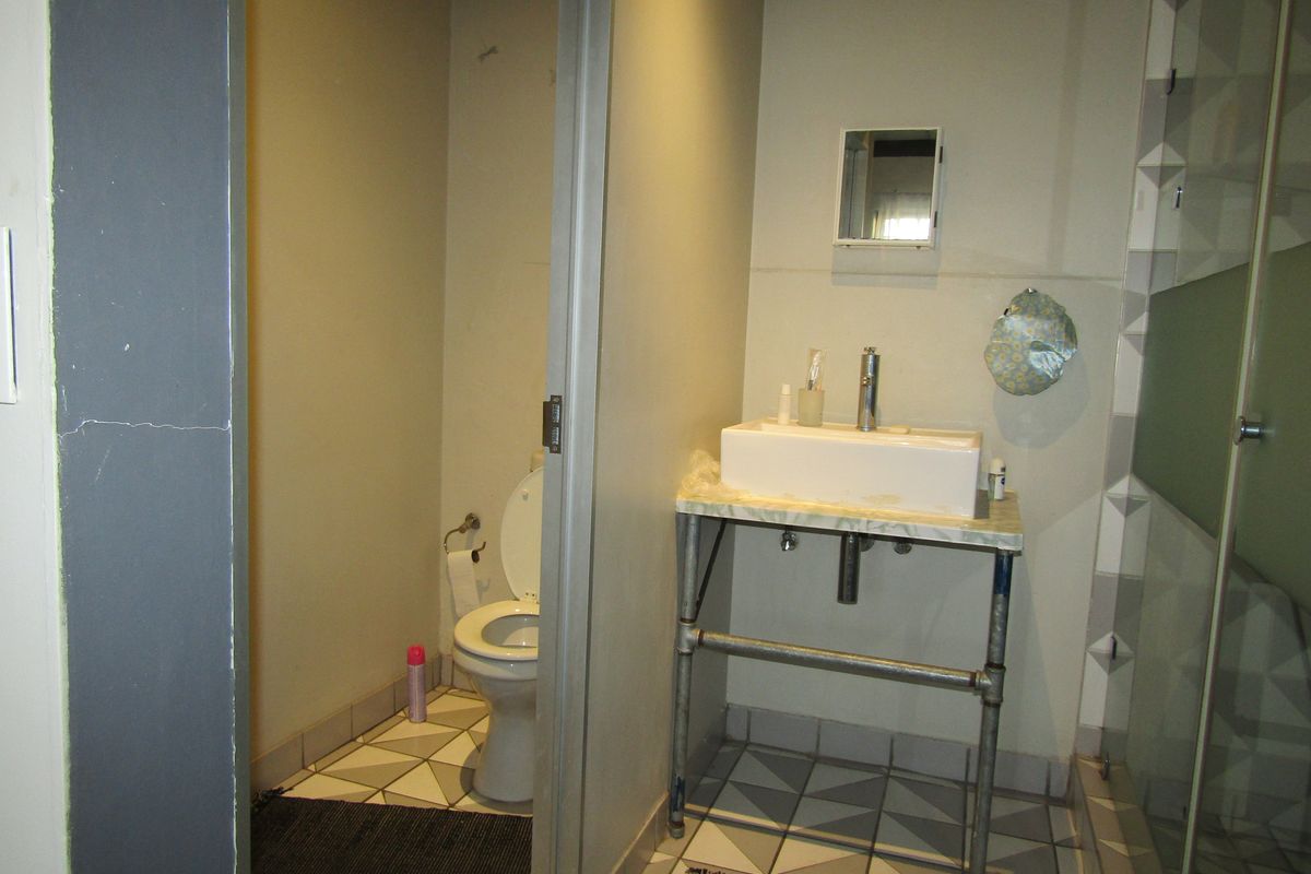 A functional bathroom featuring a vessel sink with industrial-style vanity, a separate toilet area, and geometric floor tiling.