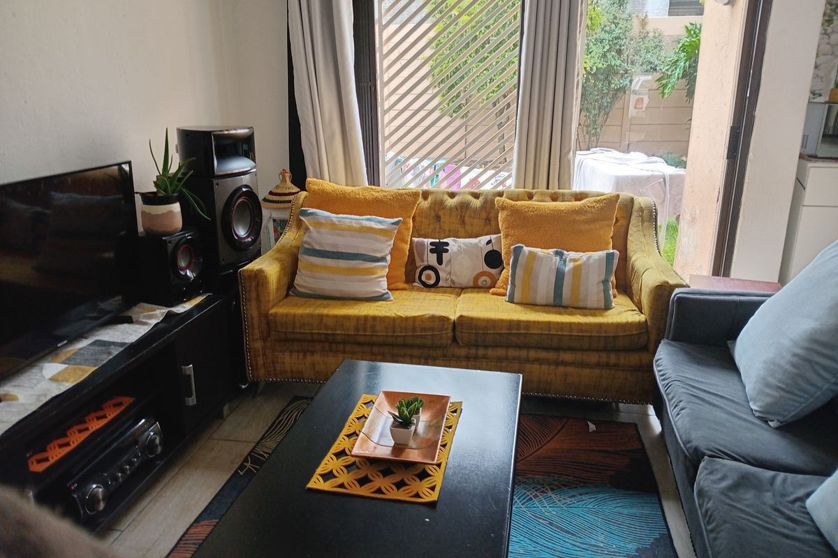 A cozy living room featuring tiled flooring and a large sliding glass door that provides access to the outdoor area.