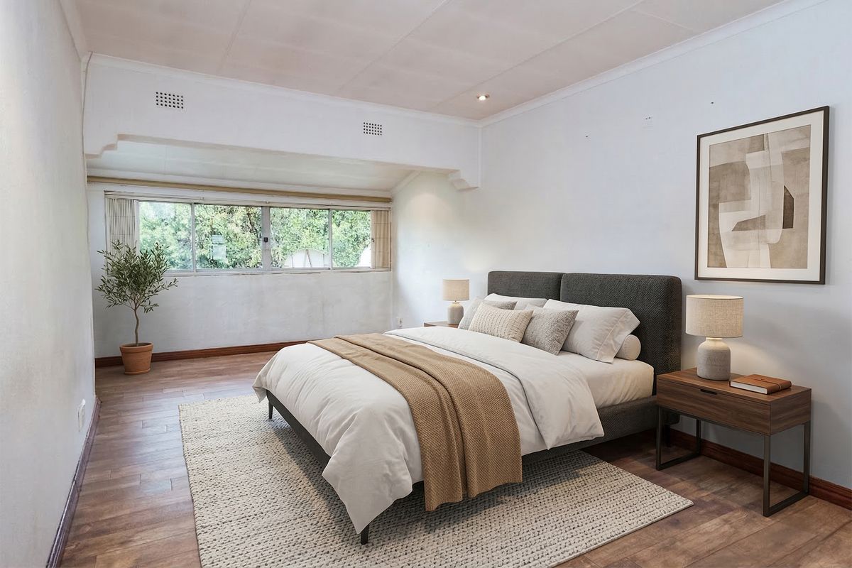 A spacious bedroom featuring wood-look flooring, large windows providing natural light, and a neutral color palette.