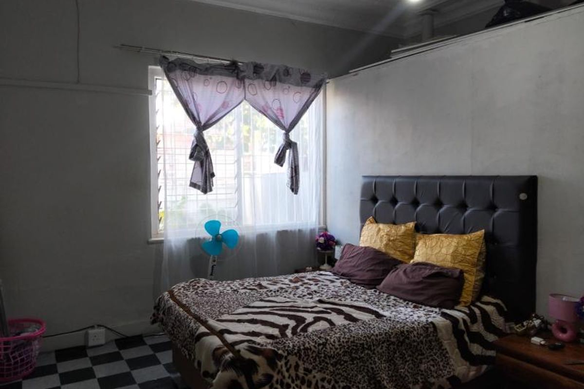 A bedroom featuring a window with security bars, tiled flooring, and a high ceiling with decorative molding.