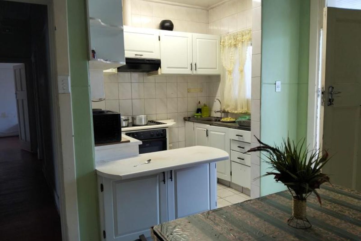 A functional kitchen featuring white cabinetry, a built-in oven and hob, and tiled splashbacks, offering a practical layout for daily meal preparation.