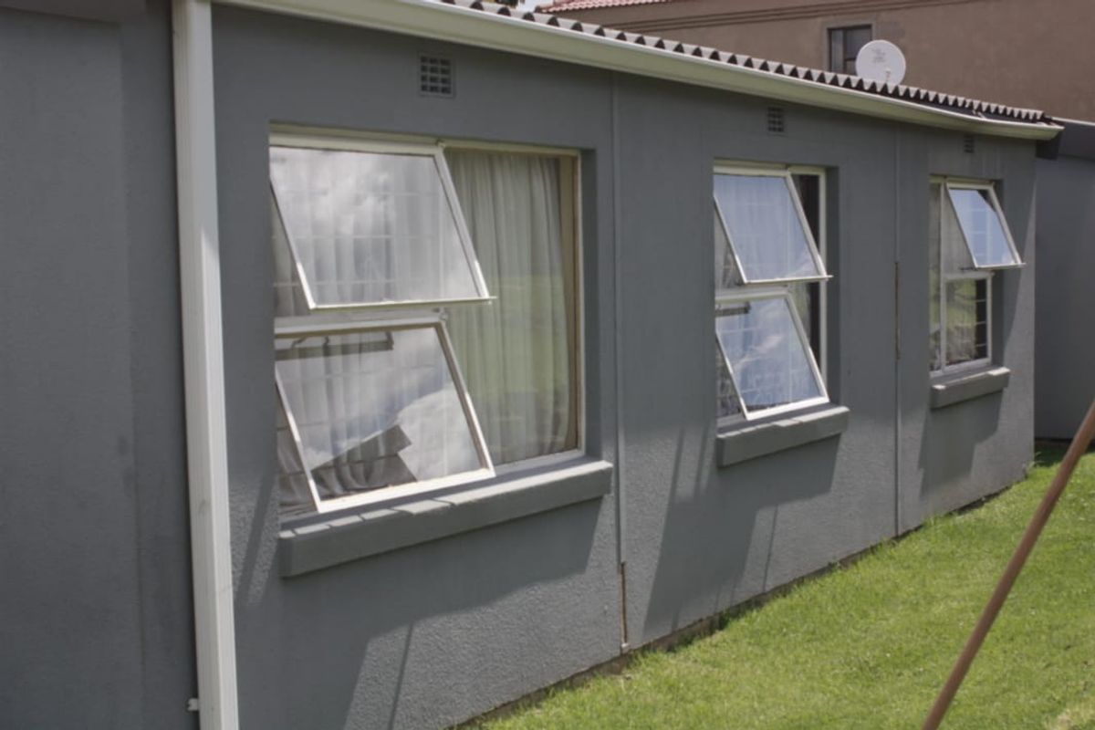 A view of the rear exterior facade of the townhouse, featuring grey painted walls, multiple top-hung windows, and a satellite dish.