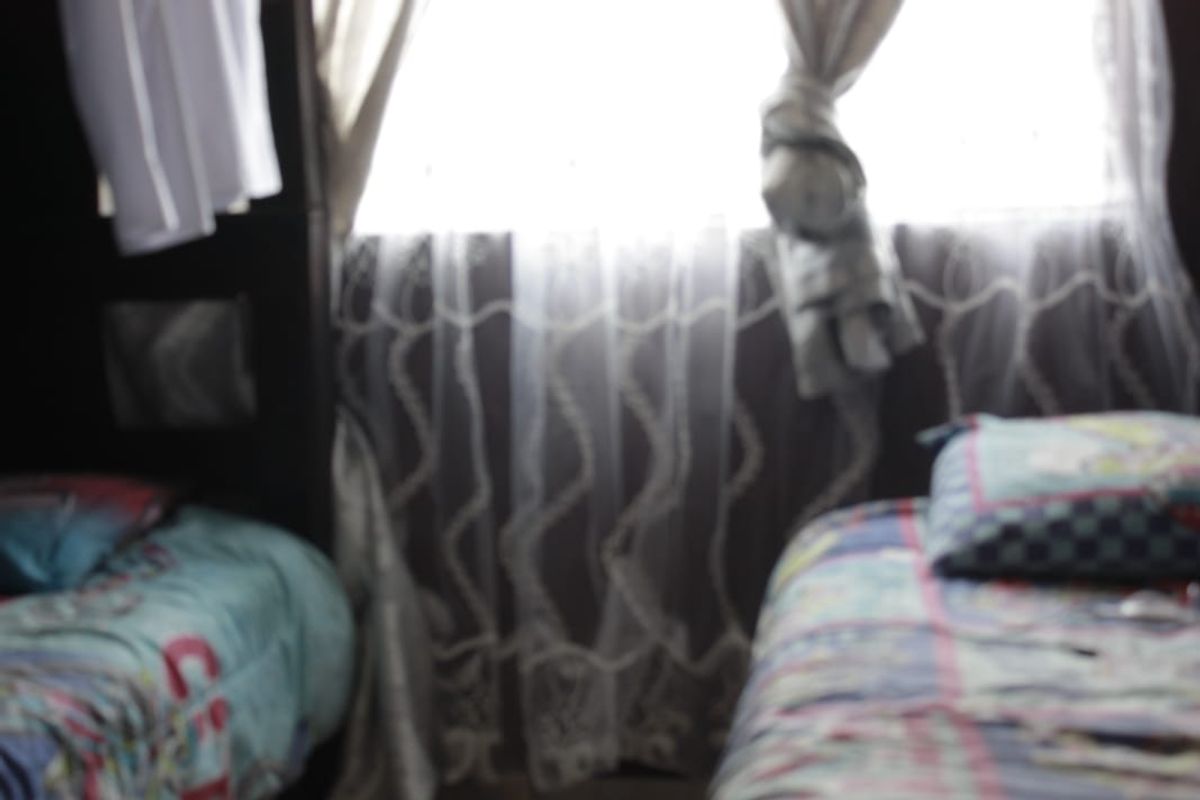 A bedroom featuring a window with curtains, captured in a blurry, low-quality image.