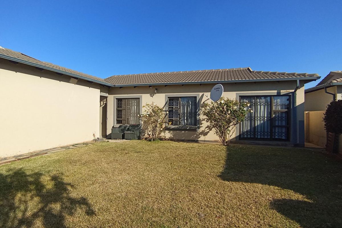 Rear view of the house featuring a tiled roof, security gates on windows and doors, and a private garden area.