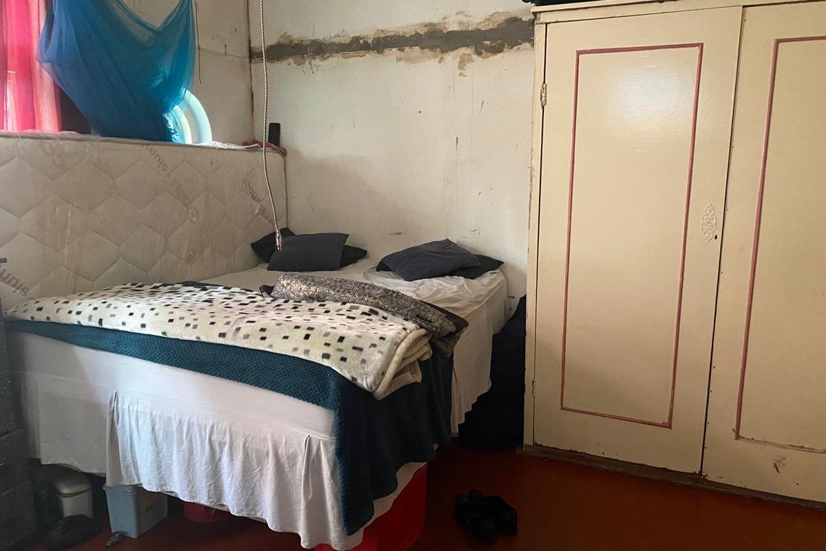 A bedroom featuring a built-in wardrobe and a circular window, currently requiring significant cosmetic repairs and wall restoration.
