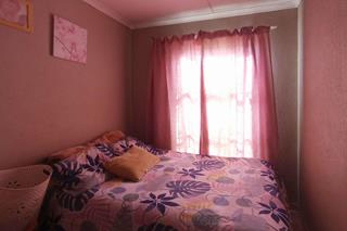 A compact bedroom featuring a window with curtains and neutral wall finishes.