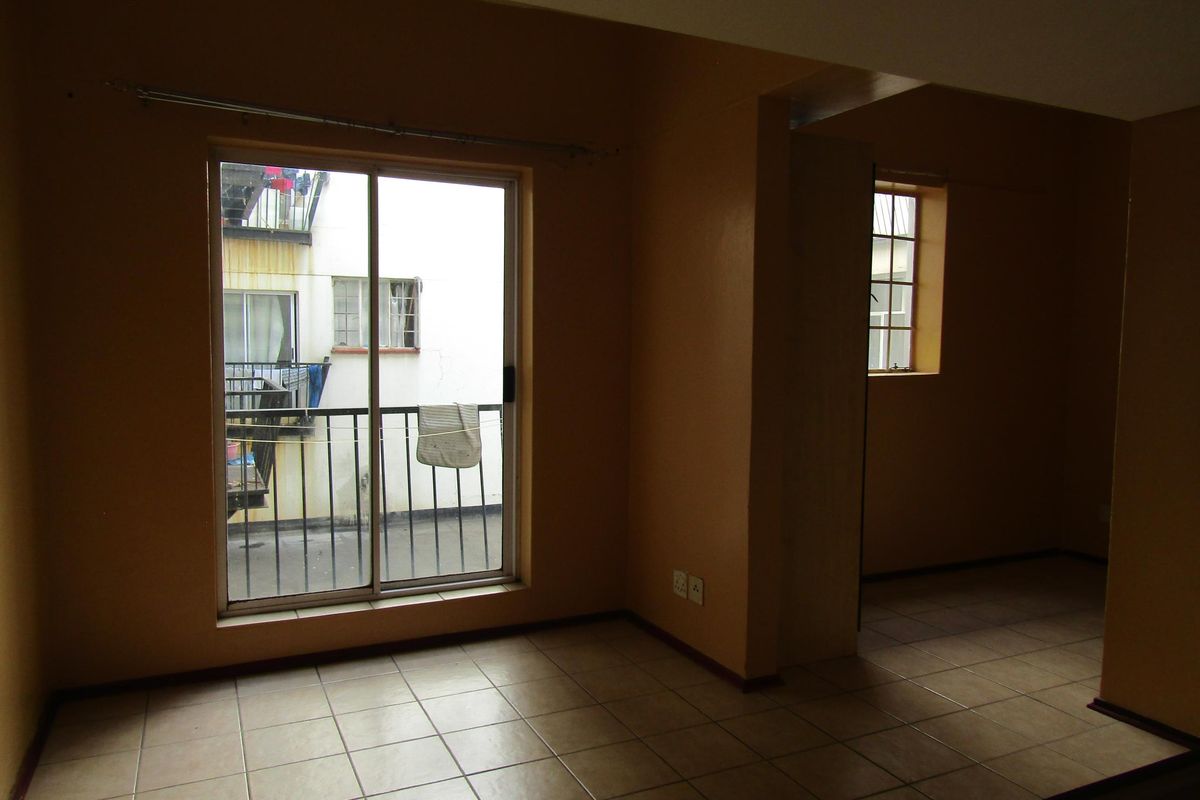 An empty living area featuring tiled flooring, a sliding glass door leading to a balcony, and neutral wall finishes.
