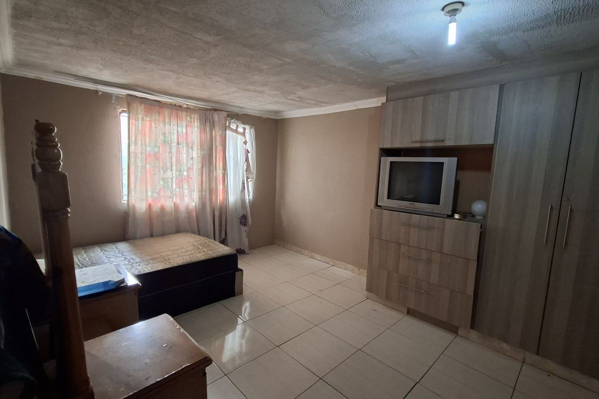 A bedroom featuring built-in wooden cabinetry and tiled flooring, requiring cosmetic updates to the ceiling and wall finishes.