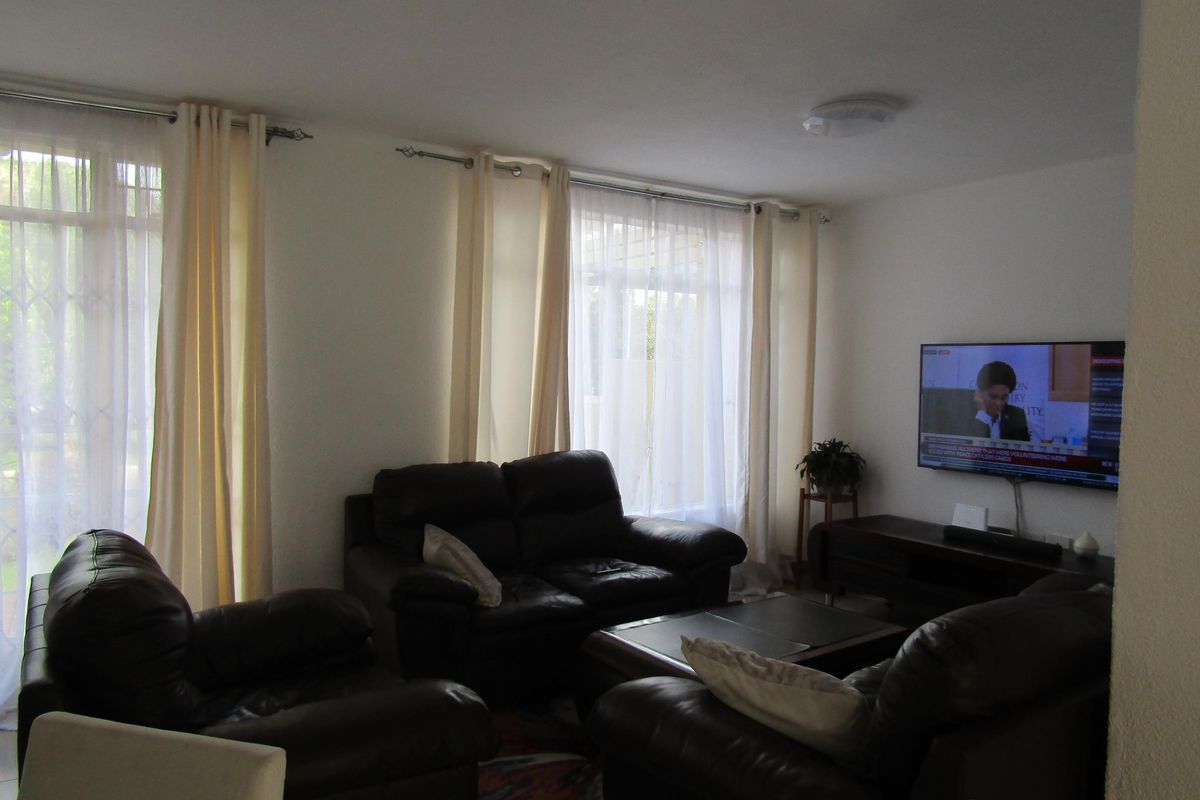A comfortable living room featuring large windows with curtains, providing natural light and a view of the exterior.