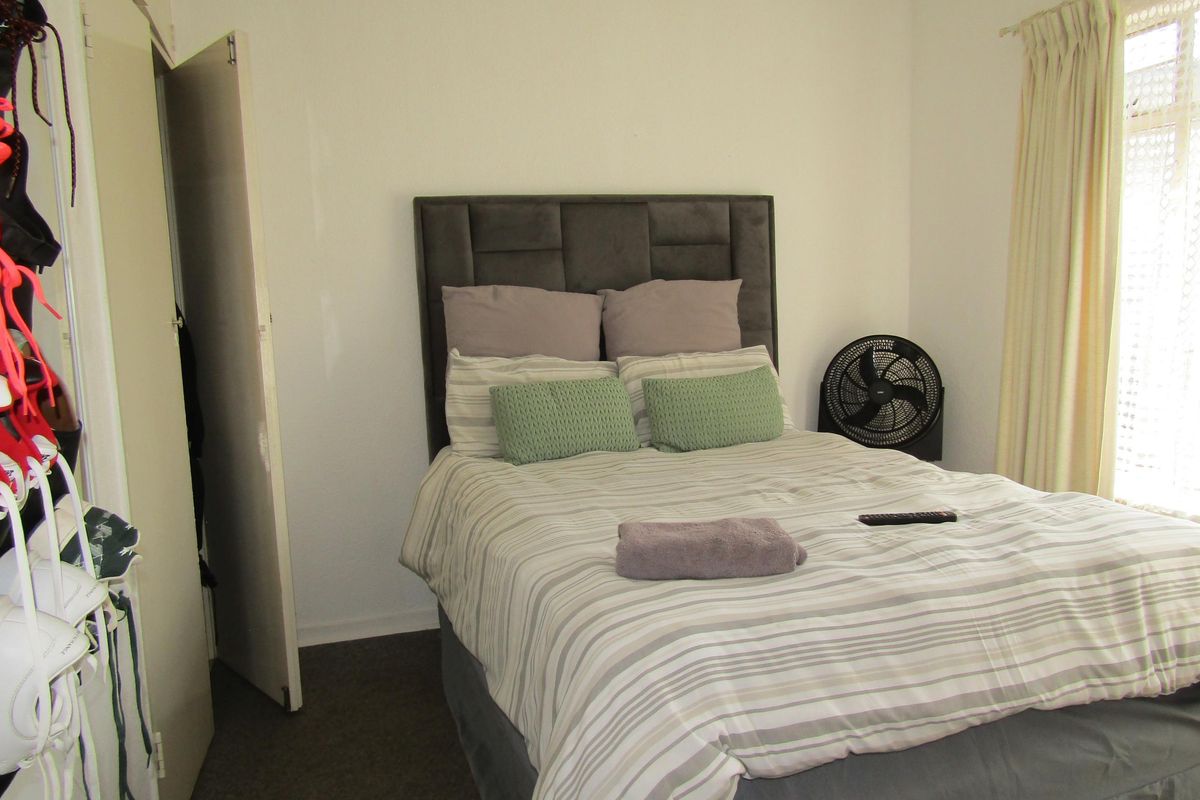 A bedroom featuring built-in closet storage and a window with curtains.