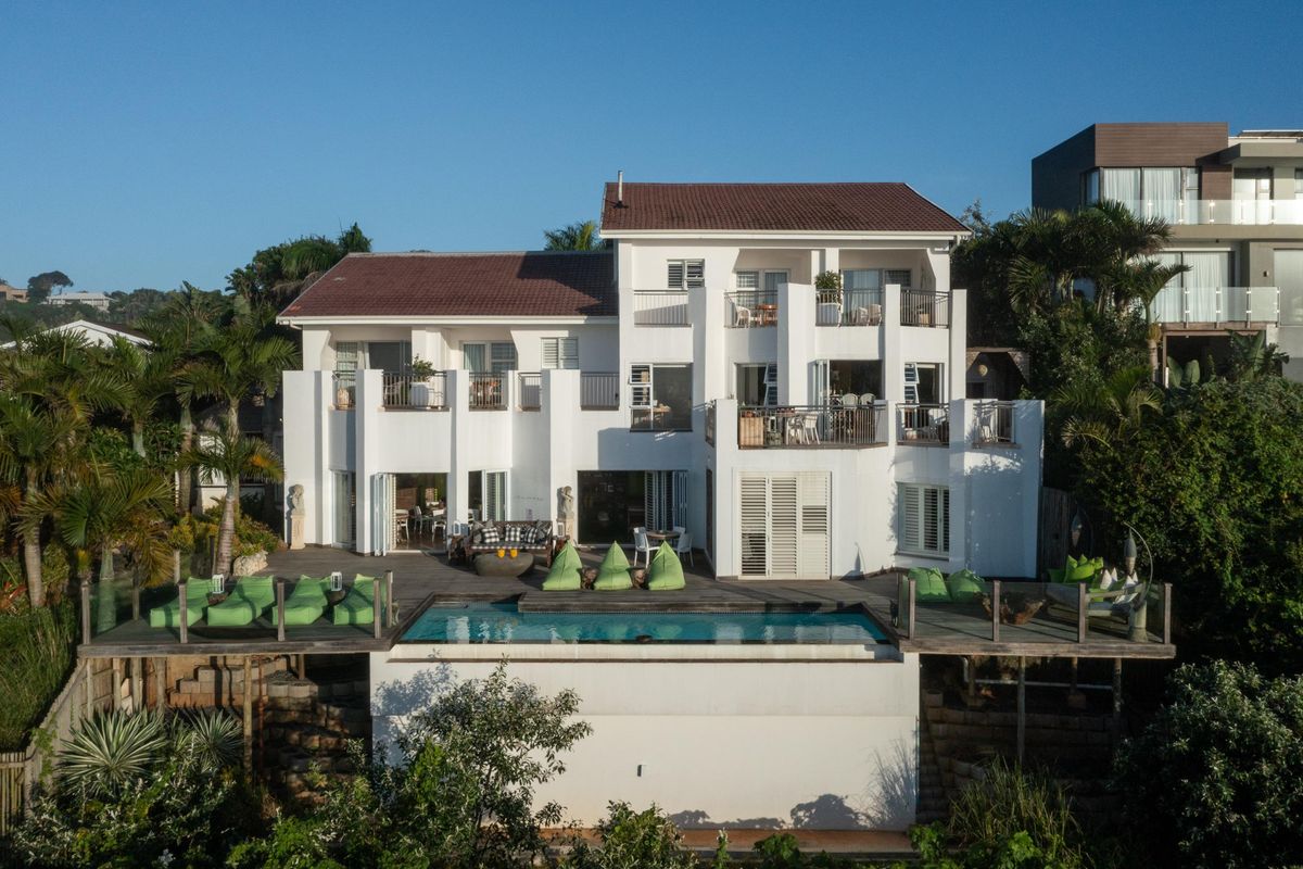 Aerial view of a multi-story residential property featuring a swimming pool, expansive timber decking, and multiple balconies with white exterior finishes.