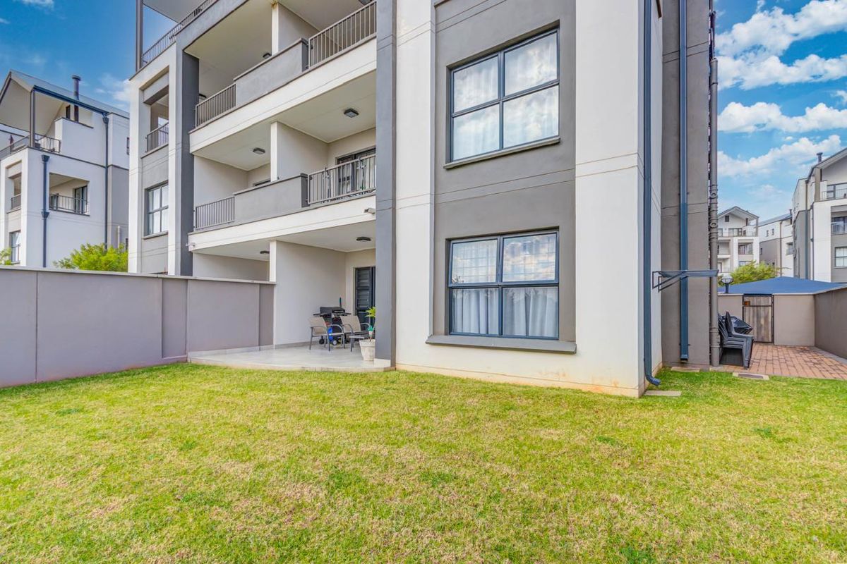 A view of the apartment building exterior featuring a ground floor patio area and a private garden space.
