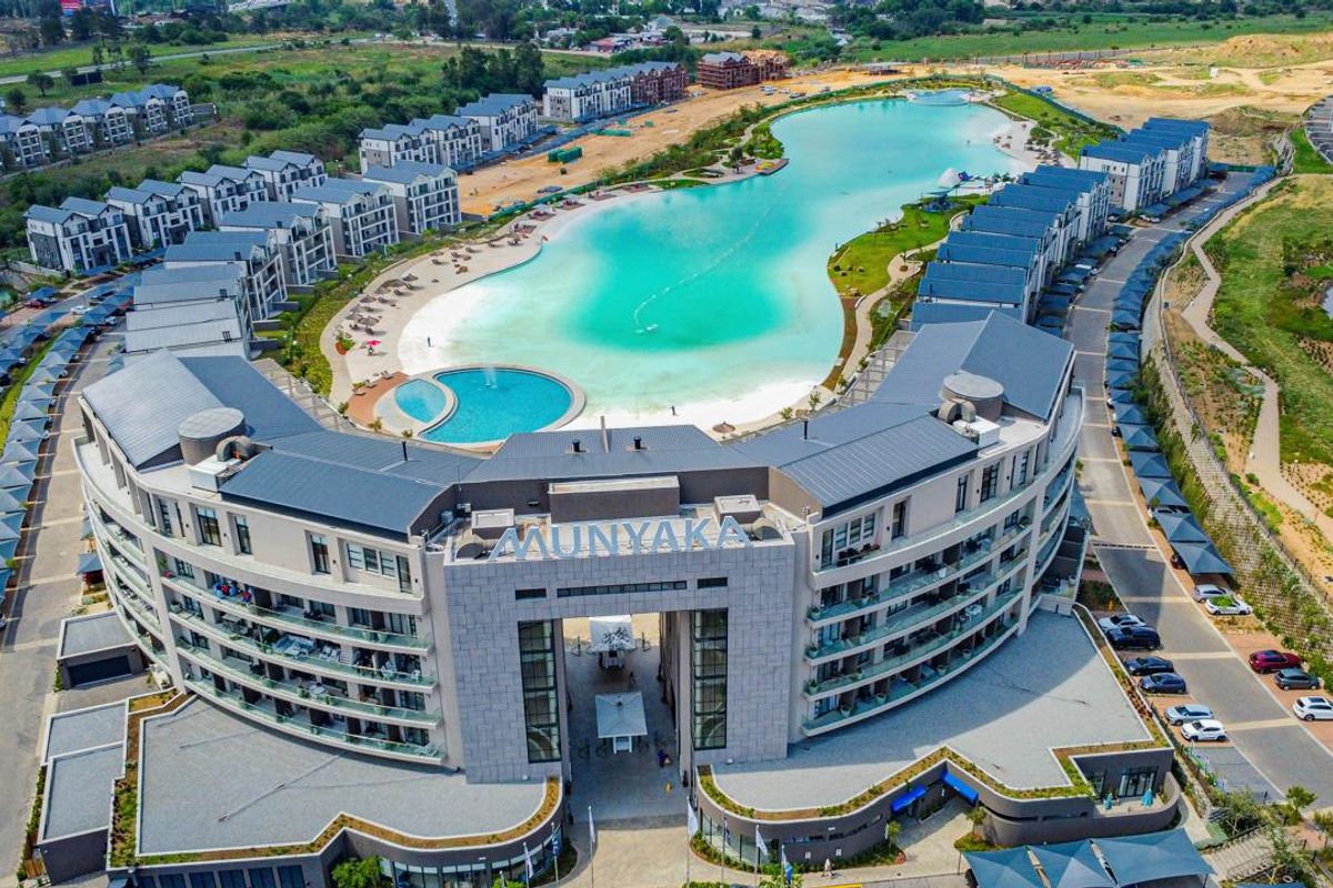 Aerial view of the modern apartment complex featuring a large central lagoon, landscaped grounds, and extensive parking facilities.