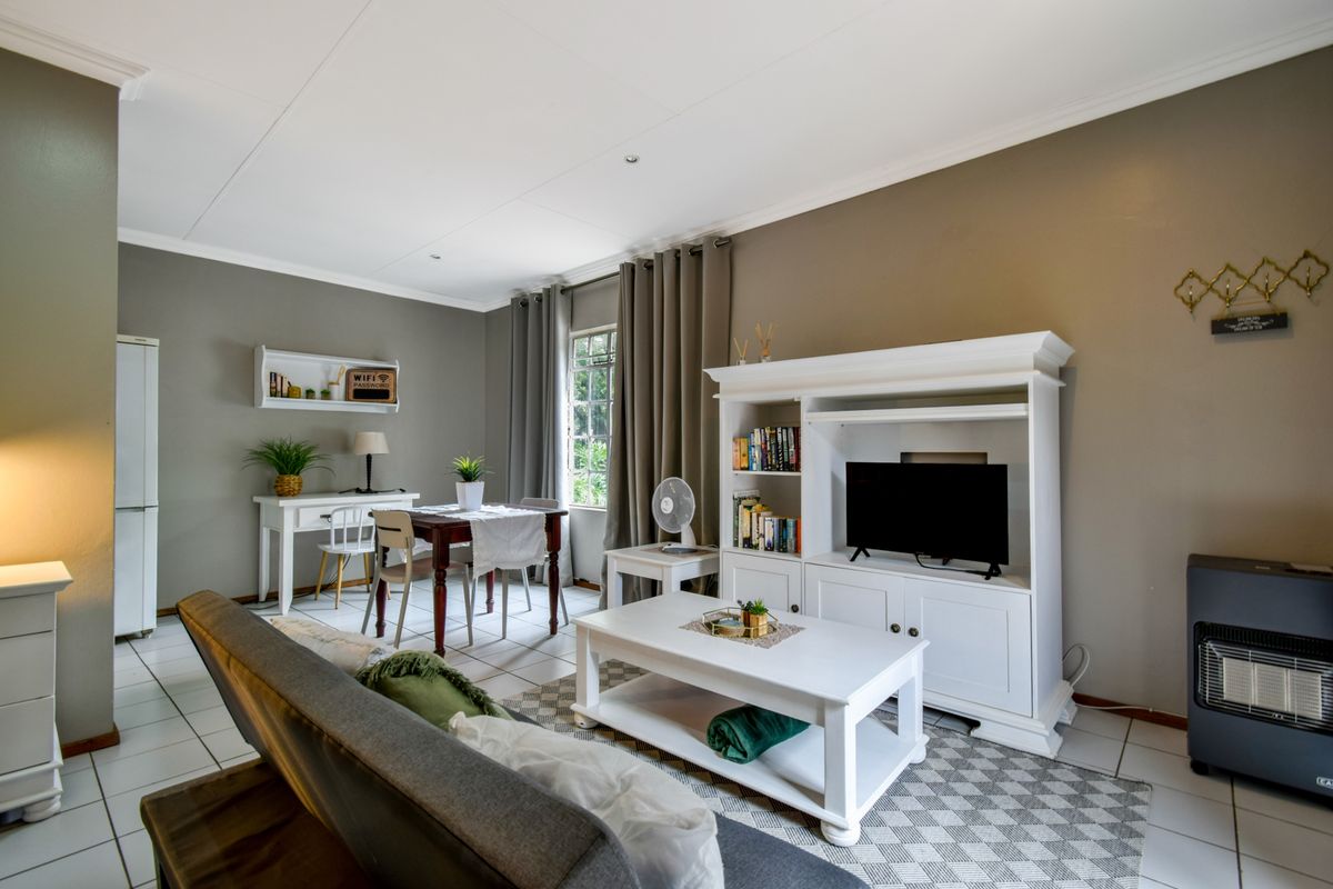 A well-maintained living room featuring tiled flooring, neutral wall tones, and recessed downlighting, creating a comfortable and functional living space.