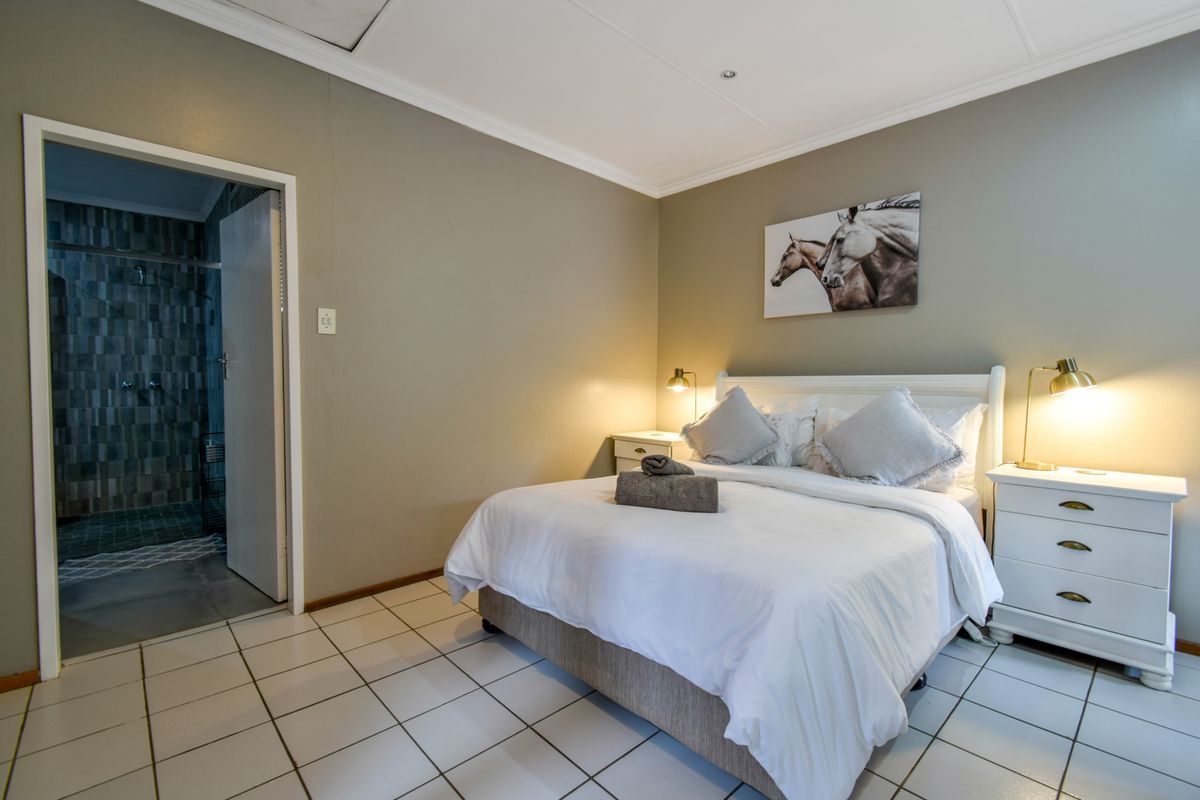 A well-maintained bedroom featuring tiled flooring, neutral wall tones, and direct access to an en-suite bathroom.