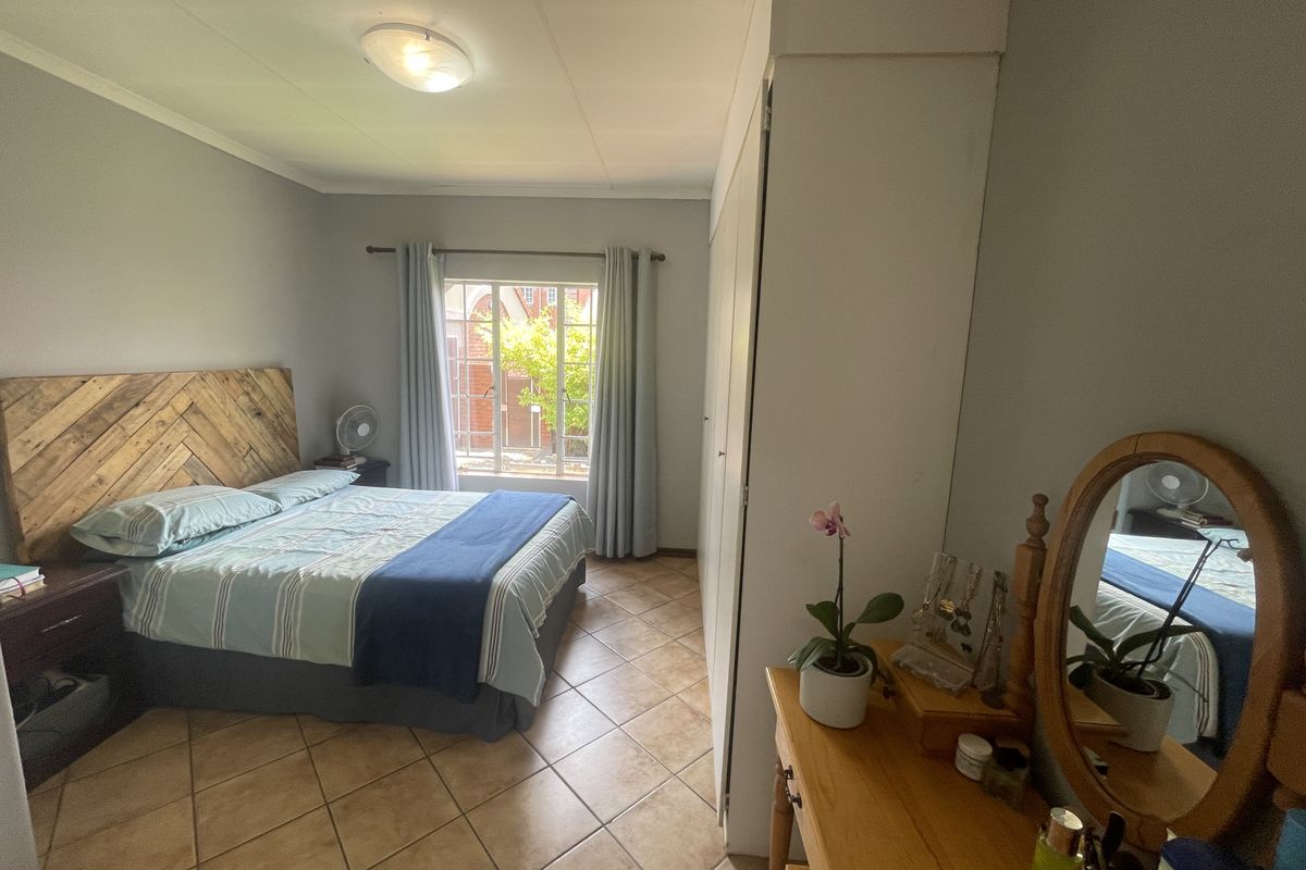 A bedroom featuring tiled flooring, built-in cupboards, and a window with natural light.