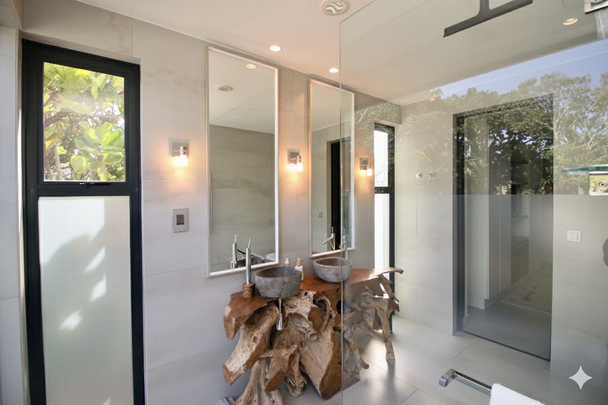Modern bathroom featuring a unique natural wood vanity with dual stone vessel sinks, large mirrors, and a glass-enclosed walk-in shower.