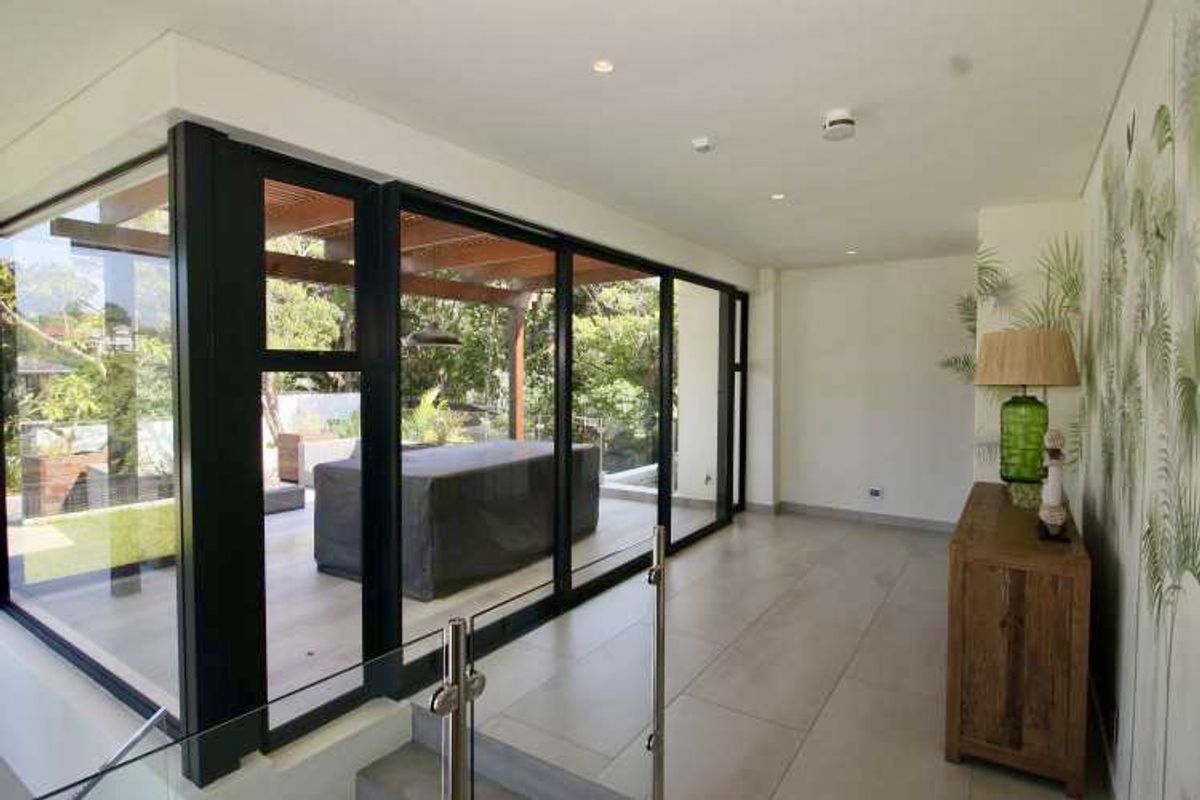 Modern living area featuring large floor-to-ceiling glass sliding doors that open onto a covered patio, creating a seamless indoor-outdoor flow.