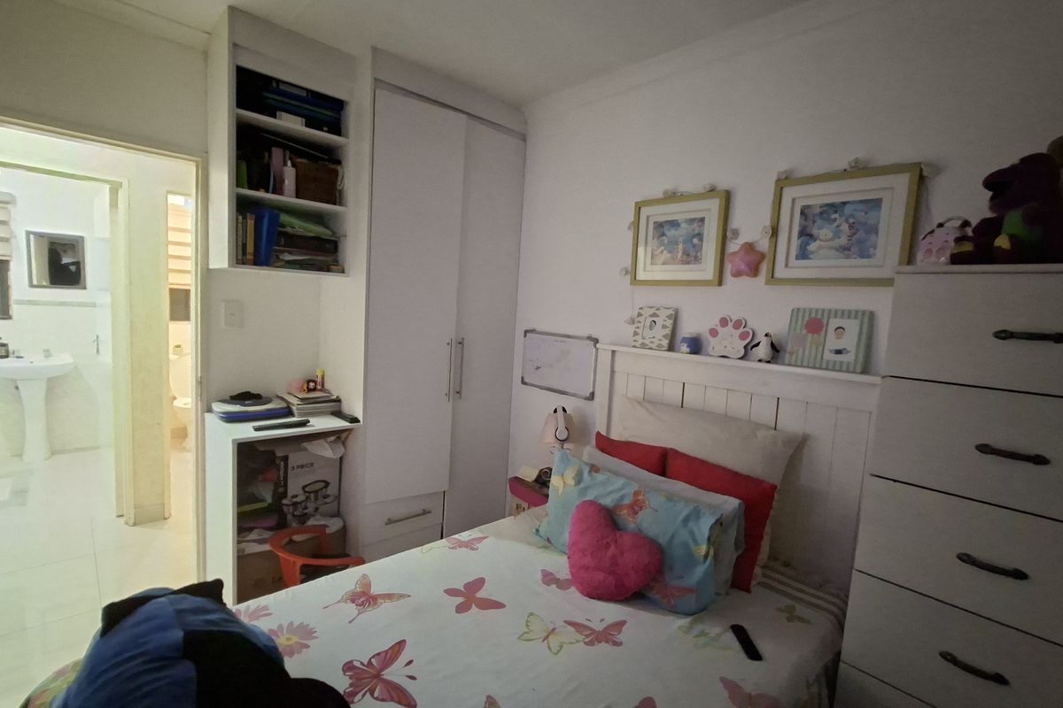 A bedroom featuring built-in cabinetry, including a wardrobe, desk, and shelving unit, with an adjoining bathroom visible through the doorway.