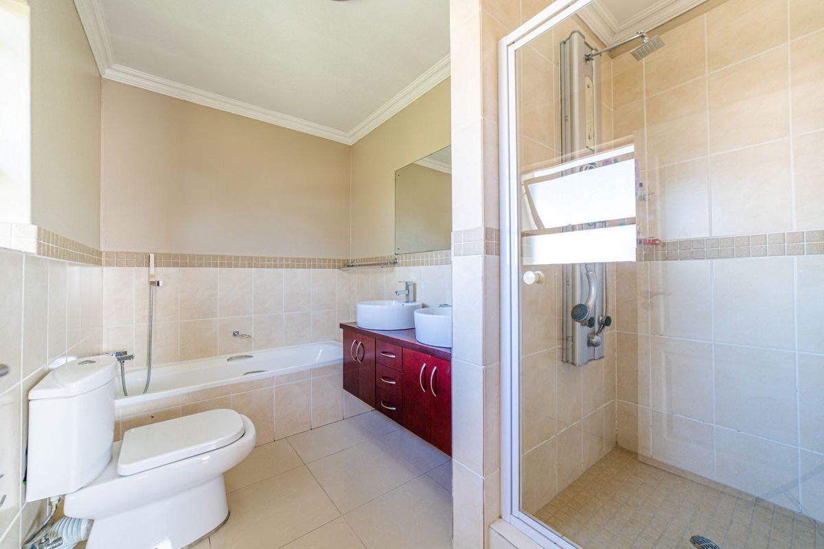 A well-maintained bathroom featuring a separate glass-enclosed shower, a built-in bathtub, and a double vanity with vessel sinks.