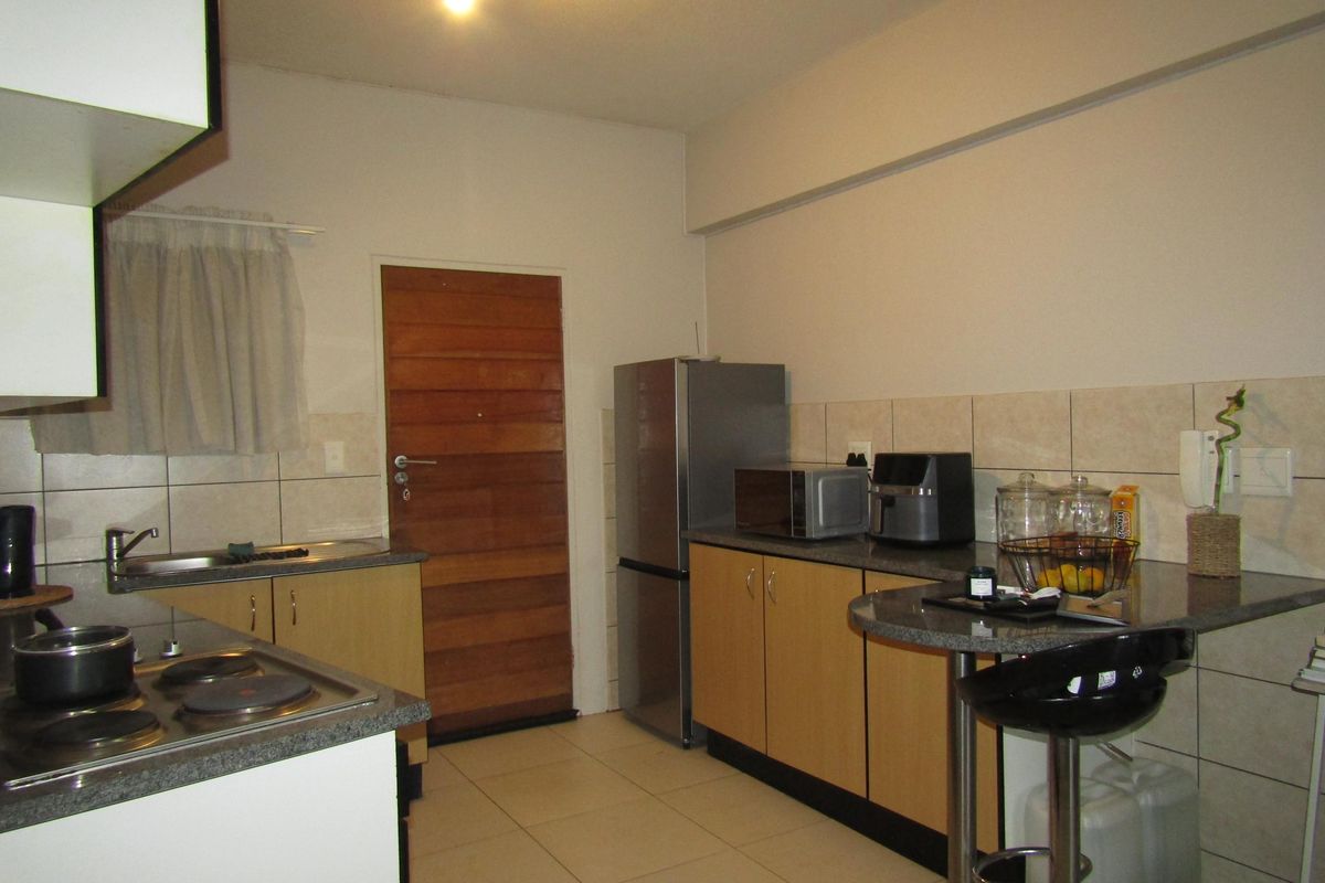 A functional kitchen featuring laminate cabinetry, stone-look countertops, a built-in electric hob, and tiled flooring, providing a practical workspace for daily meal preparation.