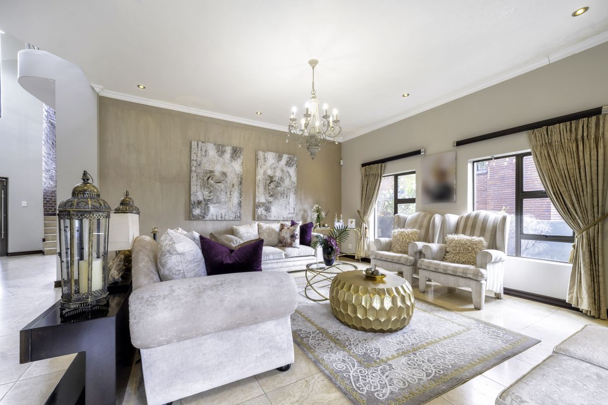 Spacious living room featuring tiled flooring, recessed downlighting, and a decorative chandelier, creating an elegant and well-maintained atmosphere.