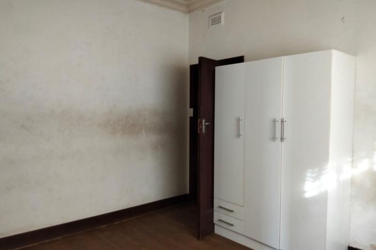 A bedroom featuring timber flooring, decorative ceiling cornicing, and a built-in wardrobe.