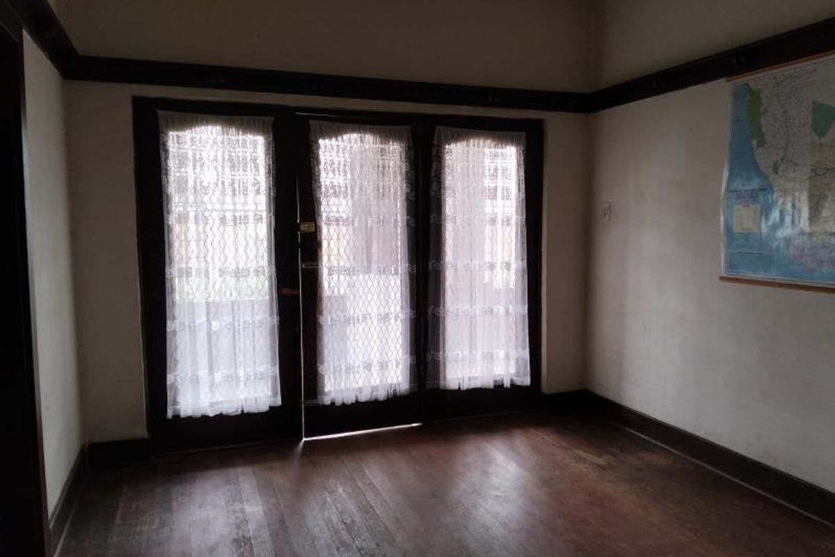 A living room featuring original timber flooring, dark wood trim detailing, and a set of glass-paned doors providing access to the exterior.