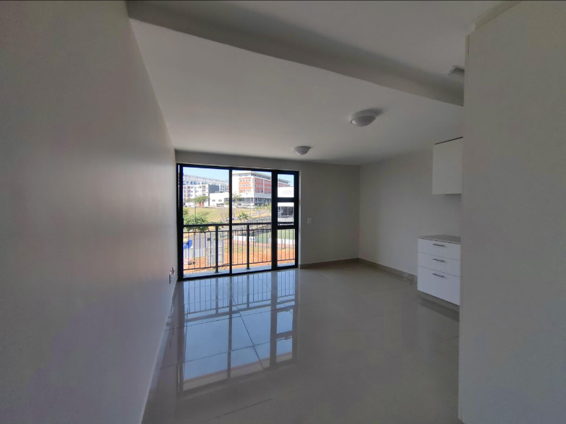 A bright, modern, and empty living area featuring polished tile floors, built-in cabinetry, and a large sliding glass door leading to a balcony.
