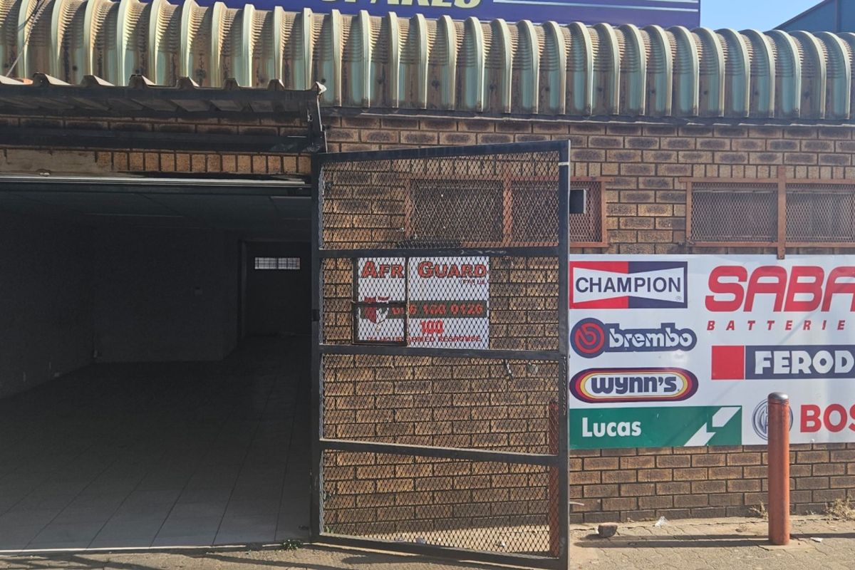 Front exterior view of a commercial property featuring a face brick facade, corrugated metal roof, and prominent signage.